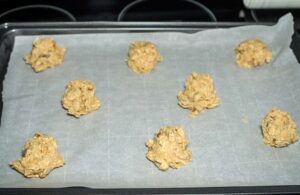 portioned oatmeal-raisin cookie dough on a lined baking sheet.