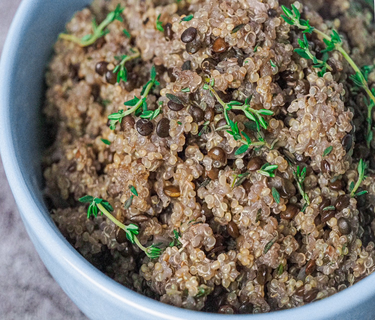 cooked quinoa and lentils in a bowl garnished with fresh thyme.