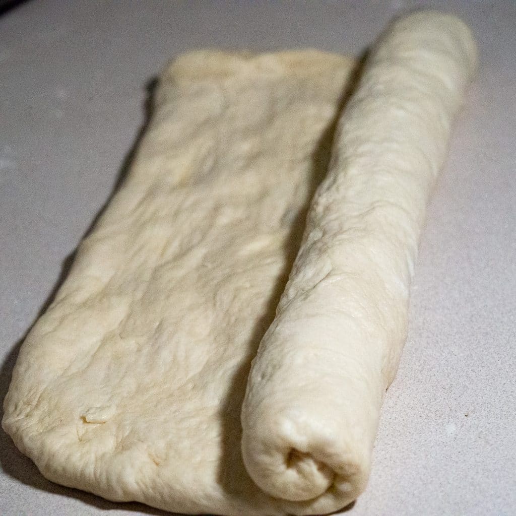 Rolling the bread dough on a a white counter top