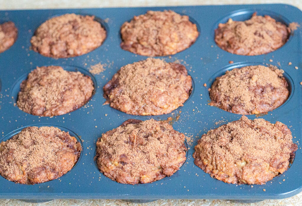 Baked breakfast apple muffin in a dark grey muffin tin.