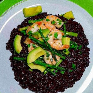 Black rice risotto top with cooked shrimp, roasted asparagus and dice avocado
