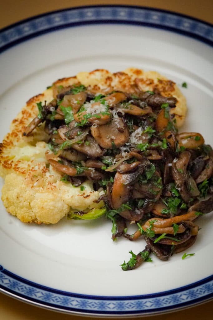 Seared cauliflower steak and top with sauteed thinly sliced mushroom with grated parmesan cheese and chopped parsley.