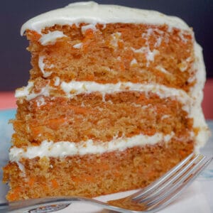 Sliced of carrot cake on a plate with dessert fork in front