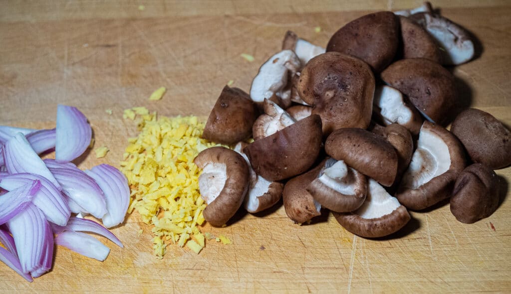 Shiitake mushroom, minced ginger and sliced shallot on a chopping board