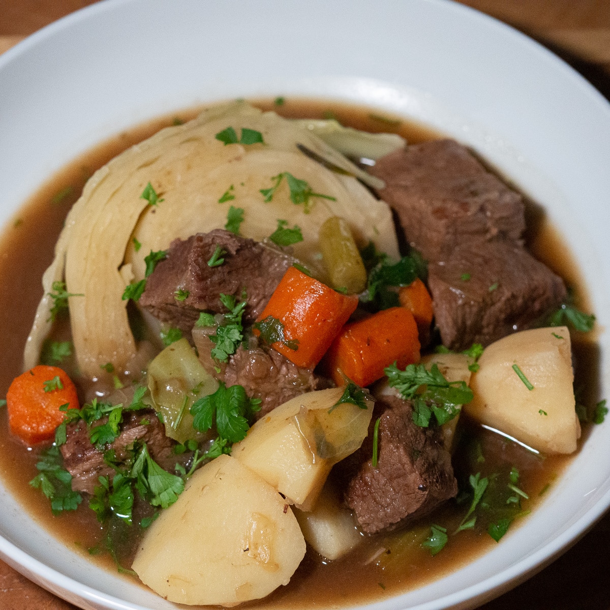 Guiness beef stew with potatoes, carrots, cabbage and it's gravy in a white plate