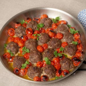 Oven roasted beef meatballs and cherry tomatoes in oven poof skillet garnish with chopped parsley