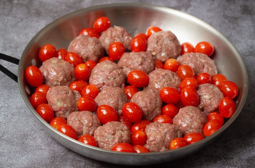 Meatballs and cherry tomatoes in oven proof skillet.