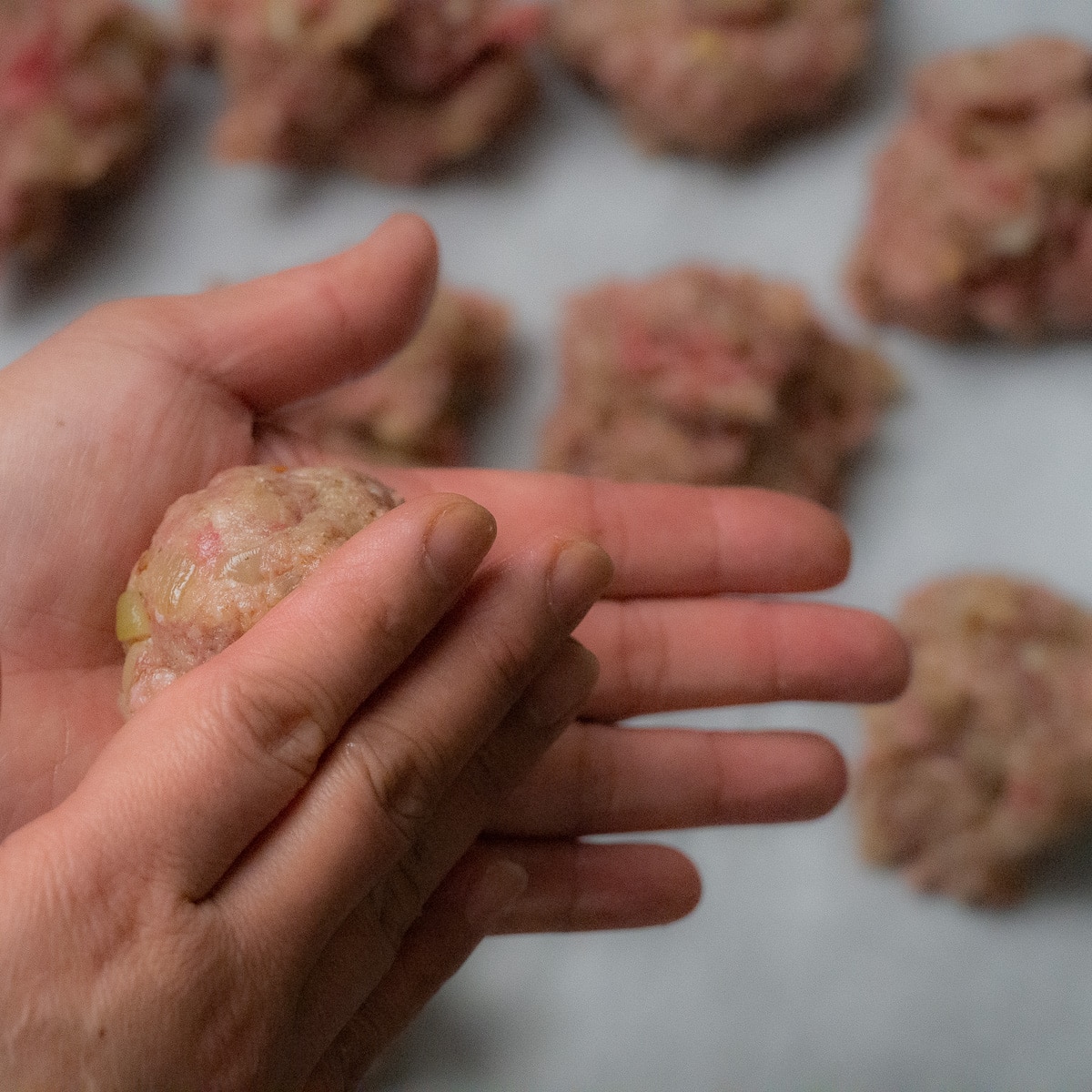 Rolling and shaping the potioned meatballs into balls.