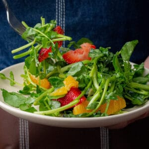watercress, orange and strawberry salad in a white plate