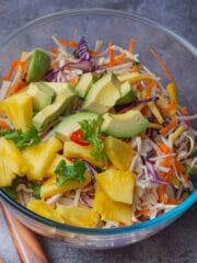 Tropical coleslaw qith diced avocado and pineapple in a clear glass serving. bowl