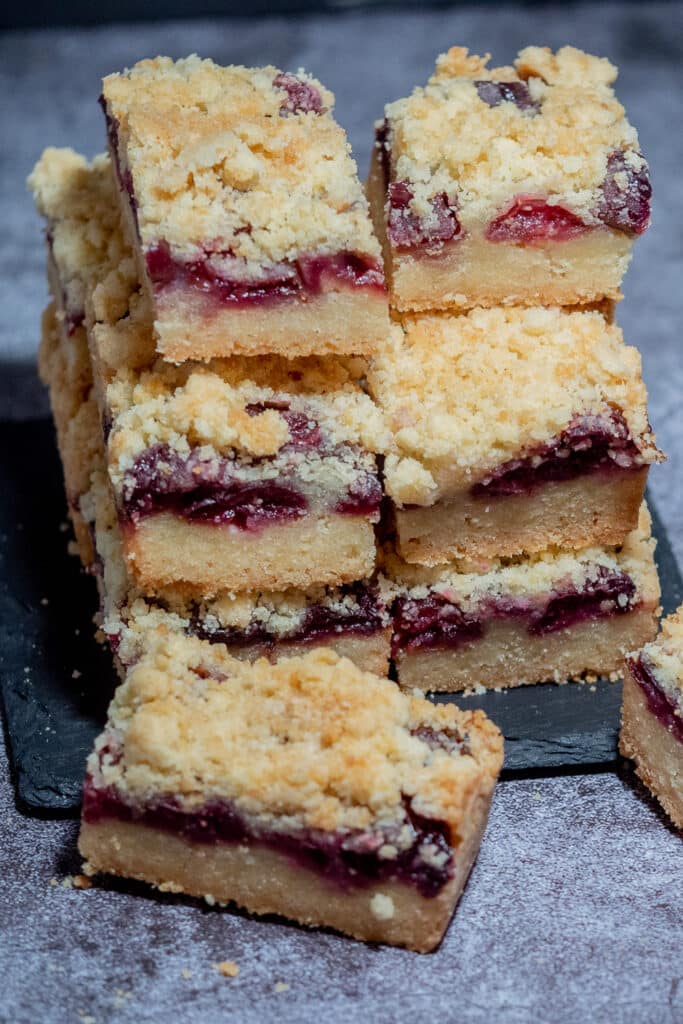 Stacks of easy cherry and thyme shortbread cookie bars place on a cement space