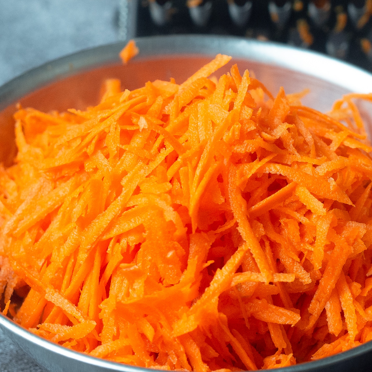 Grated carrots place in an aluminum bowl.