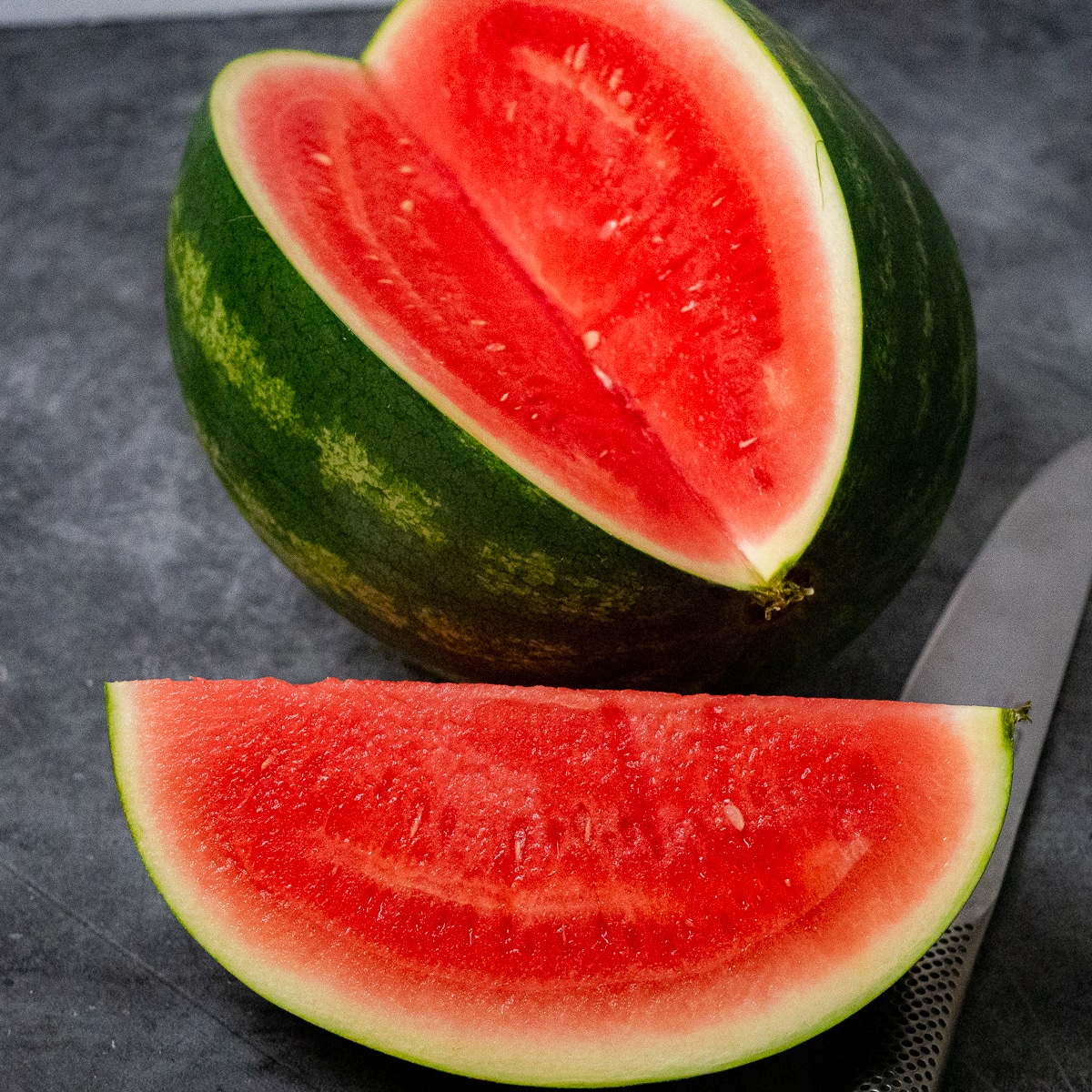 One whole watermelon with one quarter sliced.